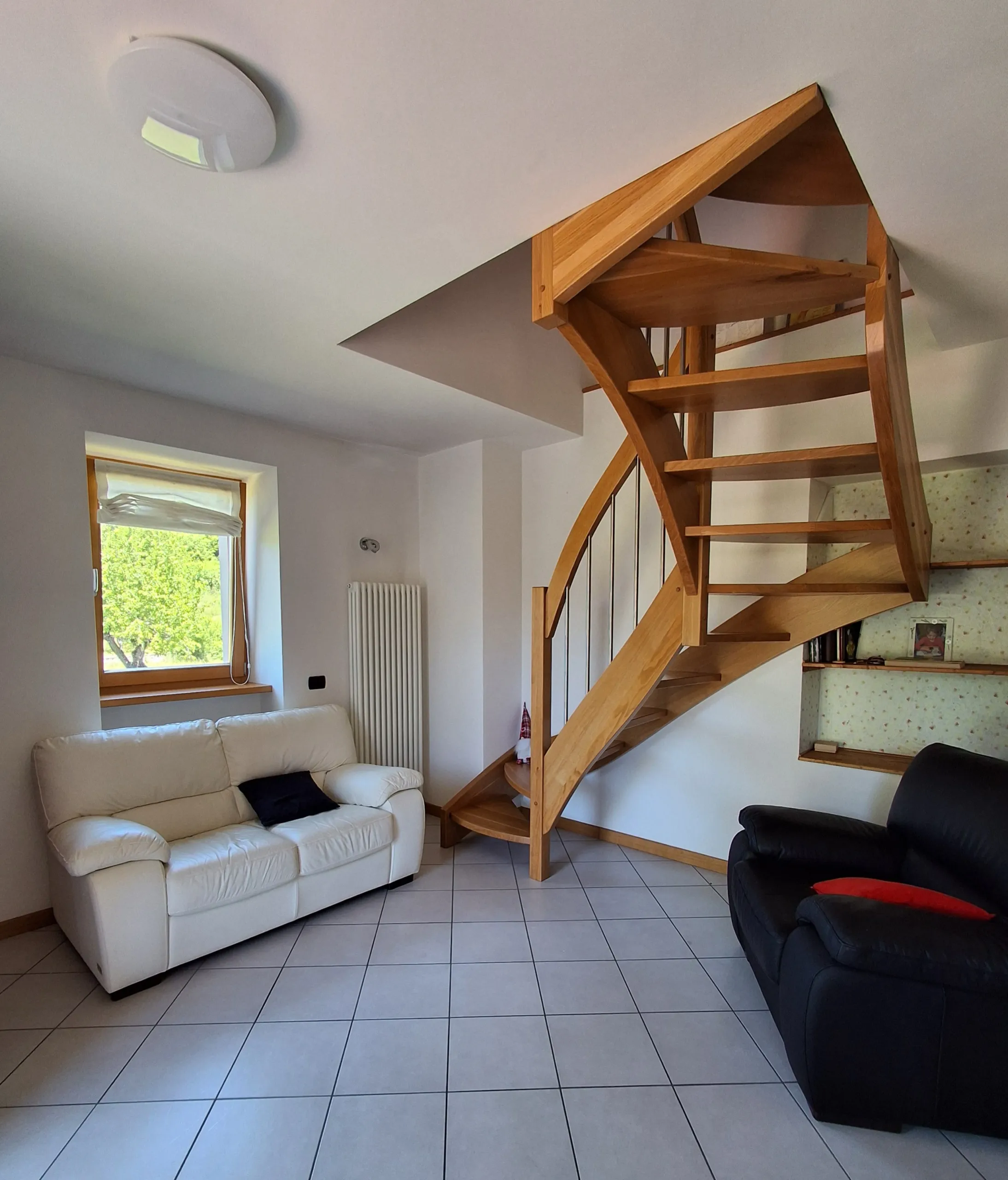Soggiorno con divani e scala interna in legno verso il piano superiore